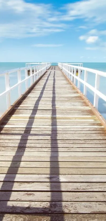 Wooden pier leading into the blue ocean under a bright sky.