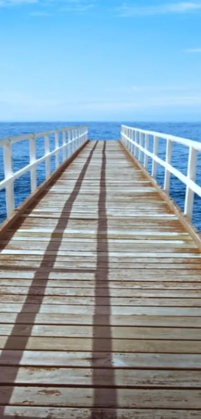 Wooden pier stretching into calm blue ocean under a clear sky.