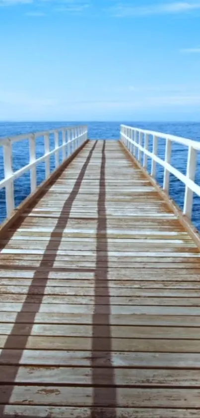 Wooden pier stretching into a calm blue ocean under a clear sky.