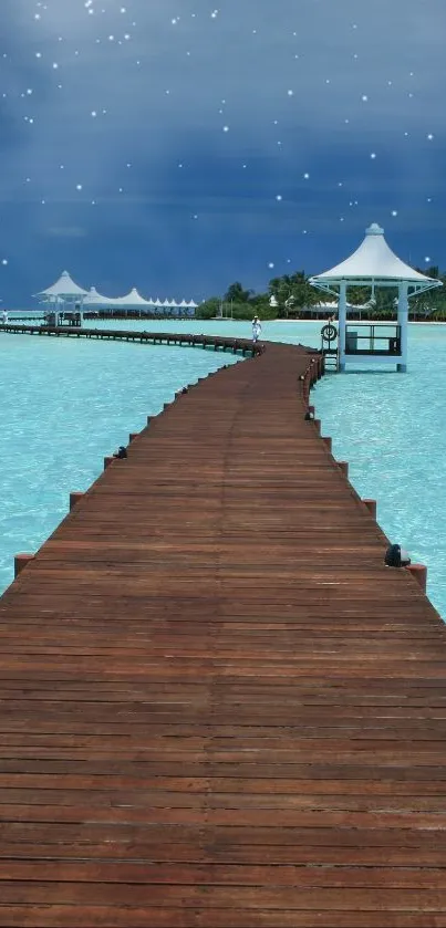 Calm ocean pier at night with starry sky and turquoise waters.