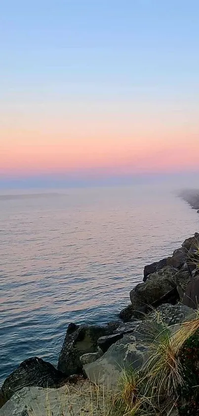 Serene sunrise over ocean with pink and blue sky.