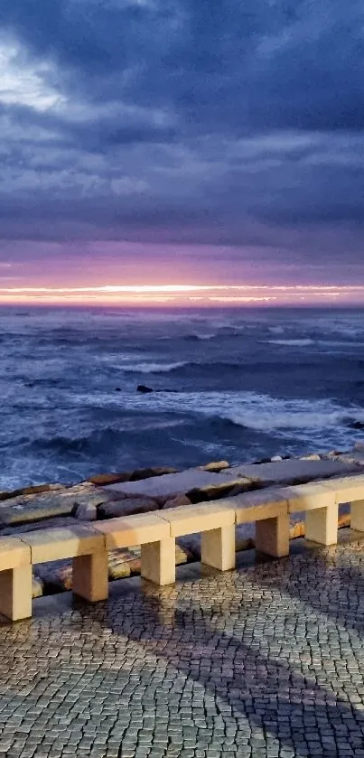 Serene ocean sunset with stone walkway reflection.