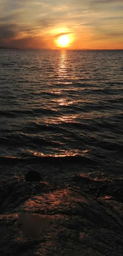 Serene sunset over ocean with golden sky and calm waters.