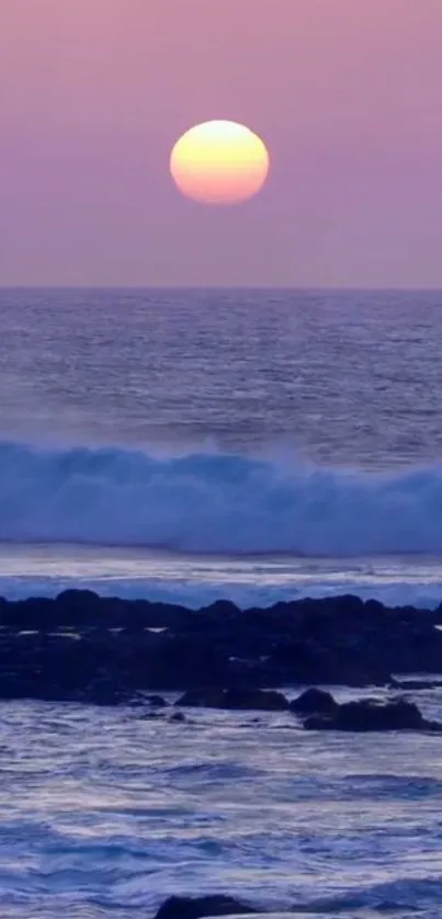 A serene ocean sunset with a pink and purple sky over gentle waves and rocks.