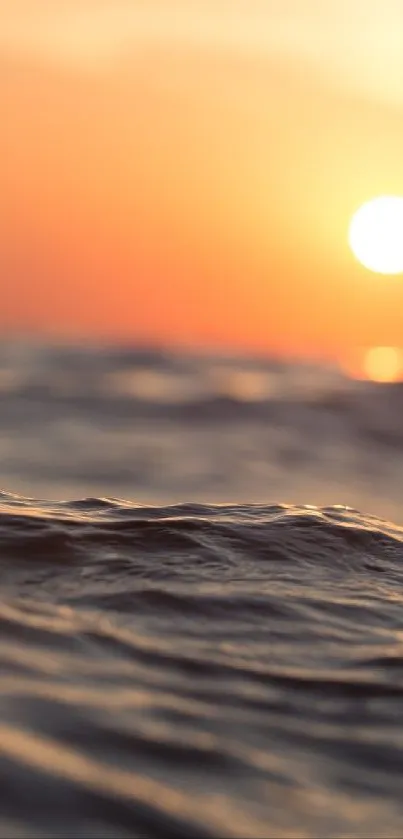 Serene sunset over the ocean with vibrant orange hues and gentle waves.