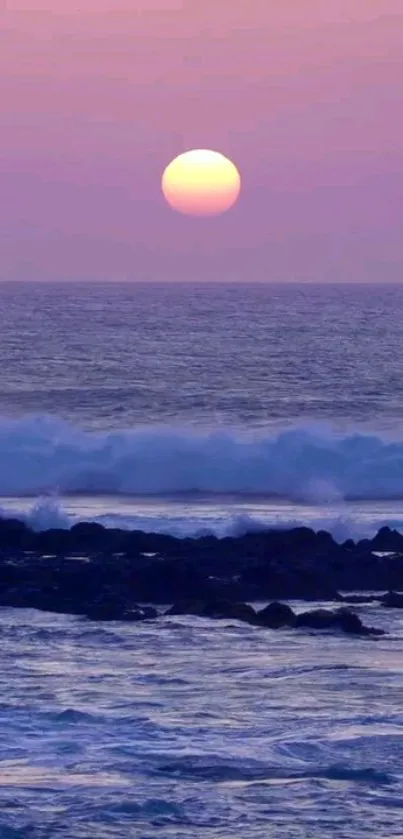 Tranquil pink and purple ocean sunset with waves crashing against rocks.