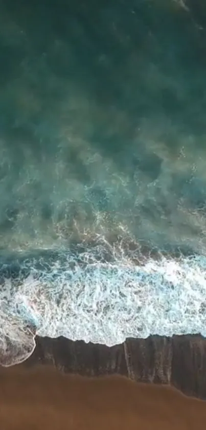 Aerial view of ocean waves meeting sandy beach.