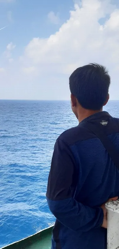 Man gazing at serene ocean under a clear sky.