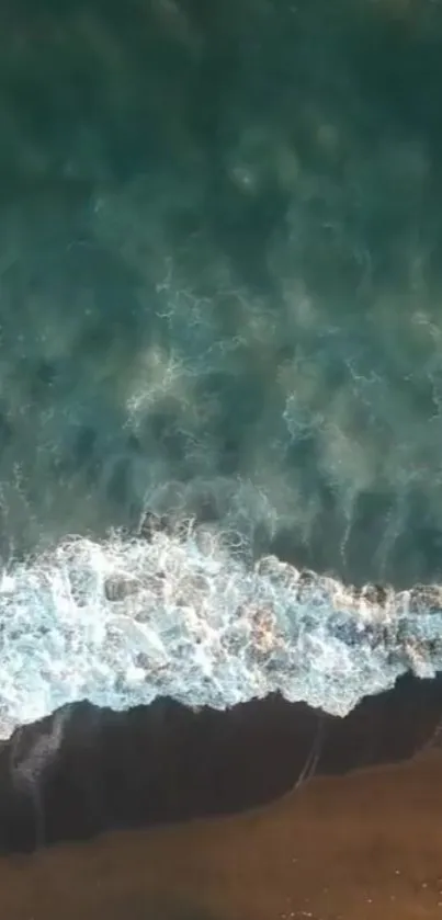 Aerial view of ocean waves crashing gently on a serene sandy beach.