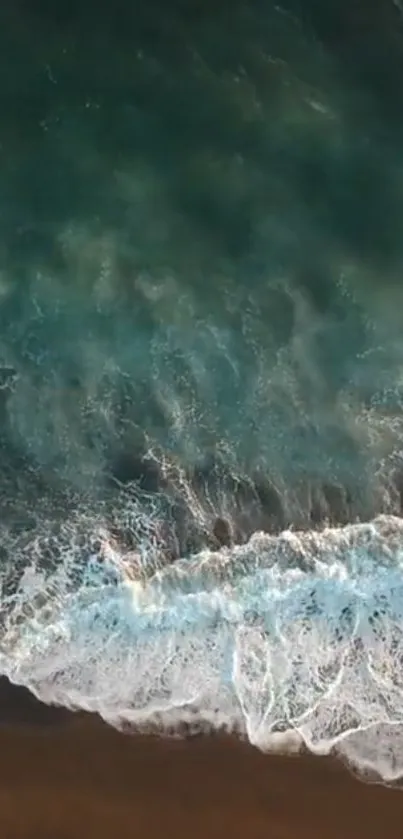 Aerial view of ocean waves crashing on a sandy beach.