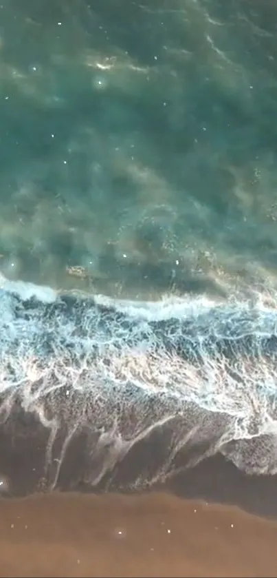 Aerial view of ocean waves gently crashing onto a sandy beach.