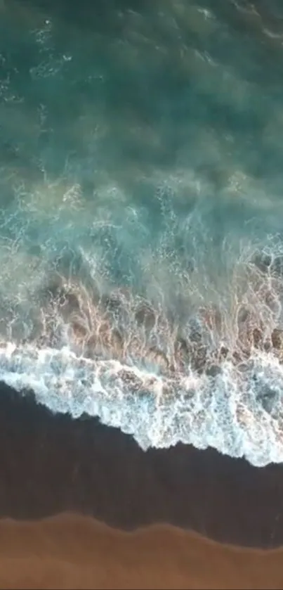 A calming aerial view of turquoise ocean waves crashing onto a sandy shore.