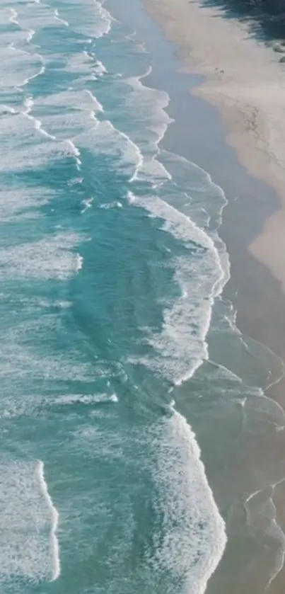 Aerial view of ocean waves meeting sandy beach.