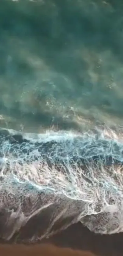 Aerial shot of ocean waves crashing softly on a beach from above.