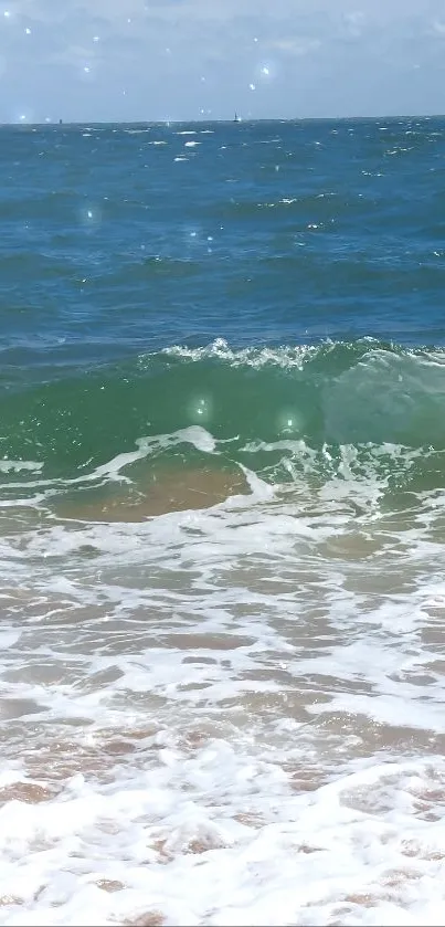 Vibrant ocean waves hitting sandy beach under a blue sky.