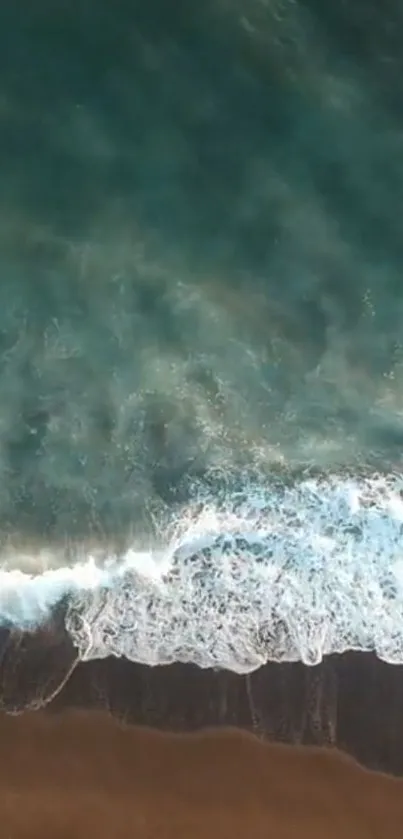 Aerial view of teal ocean waves meeting sandy beach.