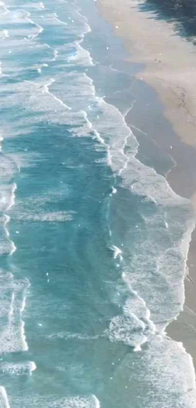 Aerial view of serene ocean waves lapping a sandy beach.