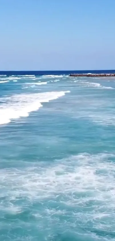 Peaceful ocean waves with turquoise water and clear blue sky.