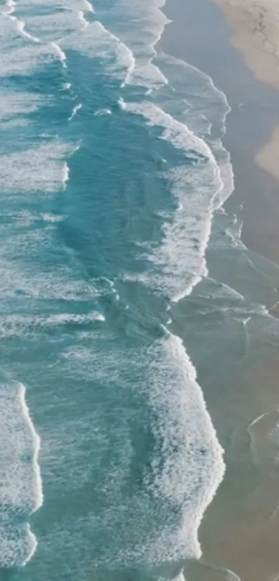 Aerial view of turquoise ocean waves meeting sandy beach.