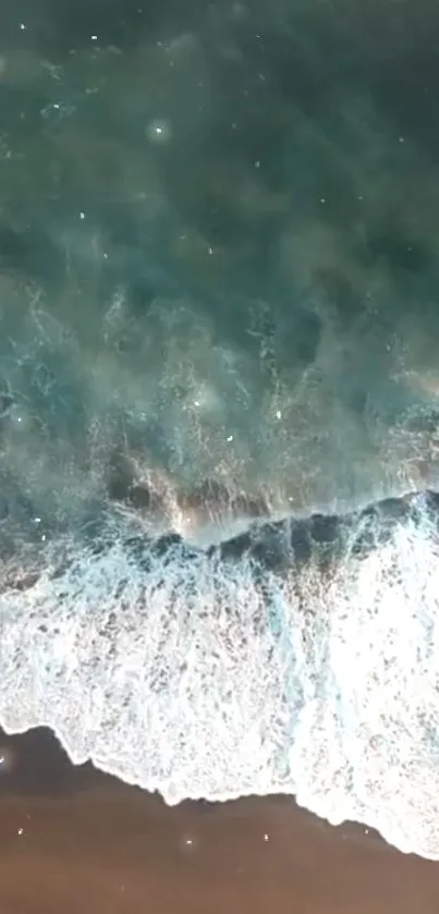 Aerial view of teal ocean waves crashing gently onto the shore.