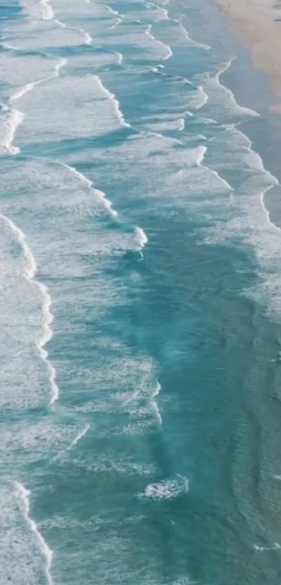 Aerial view of serene ocean waves crashing on a sandy beach.