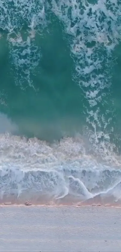 Aerial view of turquoise ocean waves gently lapping against a sandy beach.