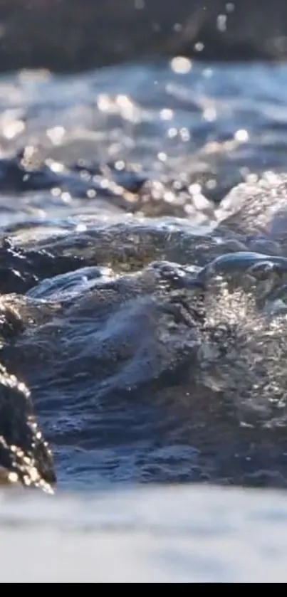 Close-up of ocean waves flowing over rocks, creating a tranquil mobile wallpaper.