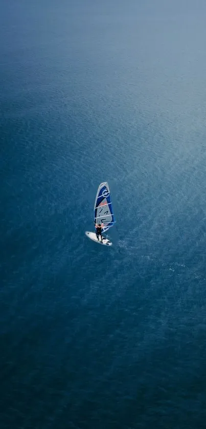 A lone windsurfer on calm blue ocean waters.