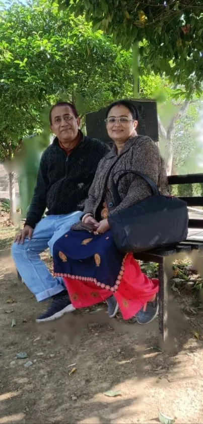 A couple sitting on a park bench surrounded by trees in natural serenity.