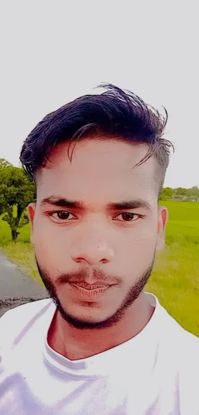 Outdoor portrait of a young man with green fields background.