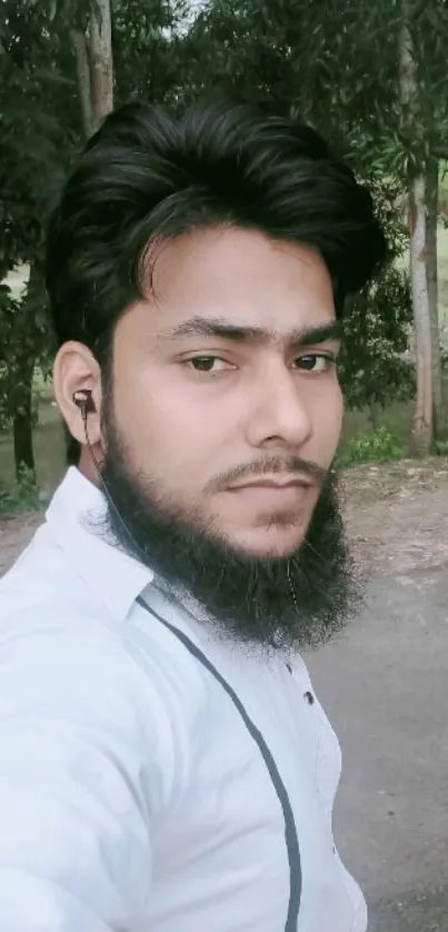 Man with beard in a nature setting, wearing earphones.