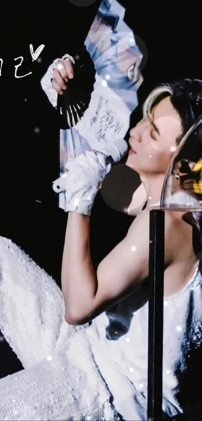 Serene performer holding a fan in a dazzling outfit against a dark backdrop.