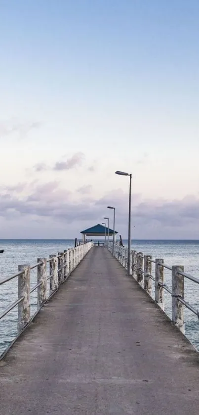 Serene pier extending into calm ocean under blue sky.