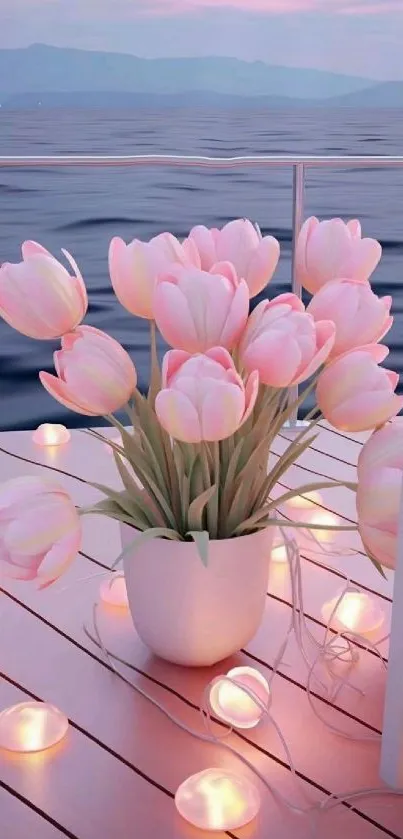 Pink tulips on a deck by the ocean at sunset, surrounded by small lights.
