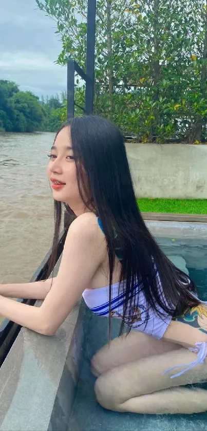 Serene woman by pool with lush greenery.