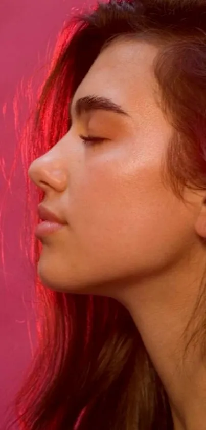 Portrait of a serene woman against a pink background.