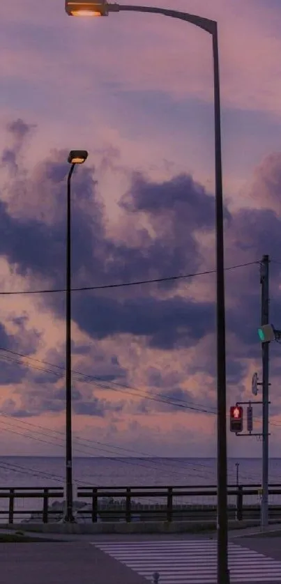 Purple dusk sky with street lamps and clouds by the ocean.