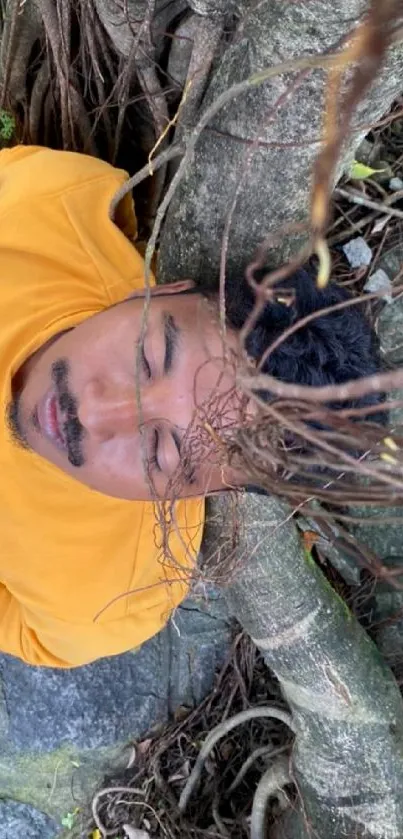 Man peacefully resting under a tree with orange sweatshirt.