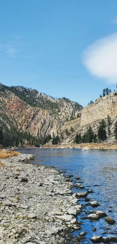 Serene river and mountain view with blue sky and rocky riverbank.