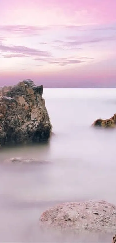 Serene sunset over rocky beach with calm ocean waters.