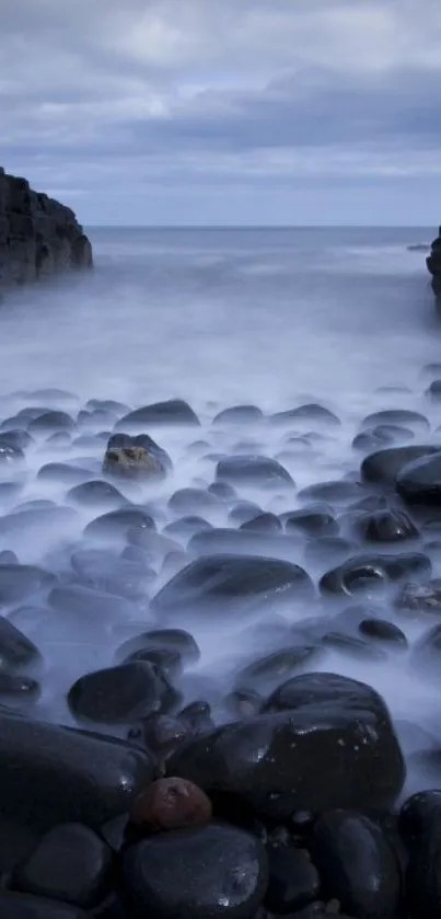 Serene ocean scene with misty rocks against a slate blue sky.