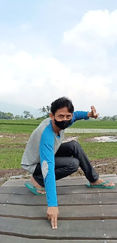 Man near tree in green rural landscape with cloudy sky.