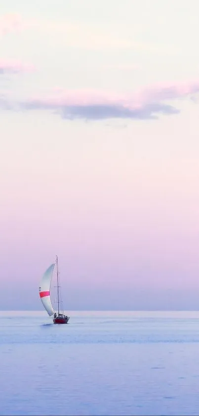 Sailboat on calm ocean at pink sunset.