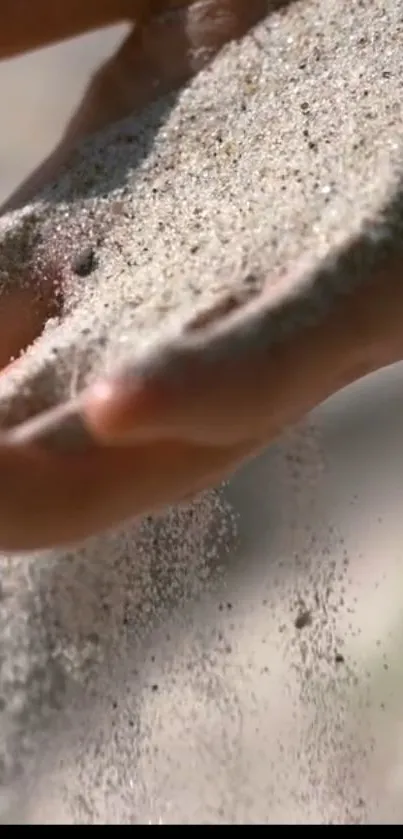 Hand gently allowing sand to flow through fingers.