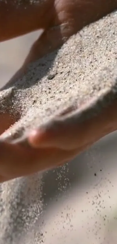 A calm and serene image of sand flowing through a hand, perfect for mobile wallpaper.