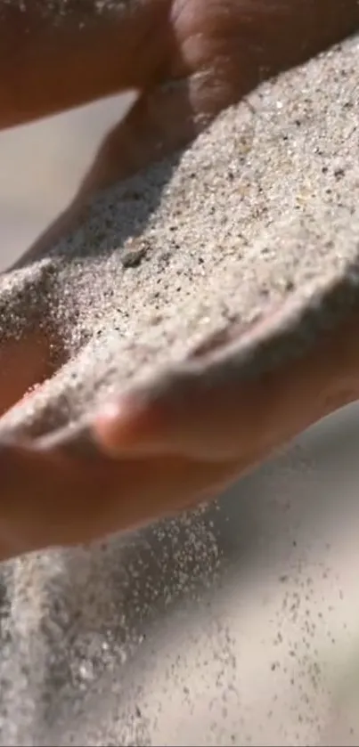 Close-up of hand letting sand flow gently through fingers.