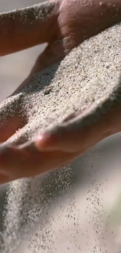 Hand letting sand flow gently through fingers, capturing serenity.