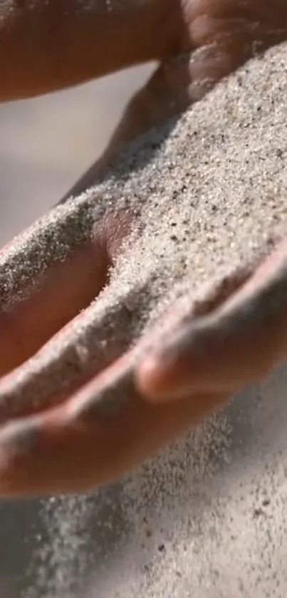 Close-up of hand letting sand flow with a serene, natural backdrop.