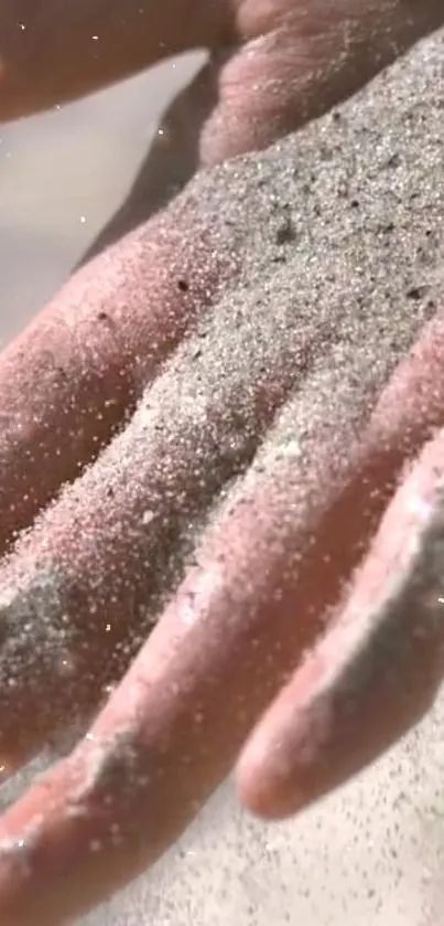 Close-up of a hand with sand delicately covering it, under soft light.