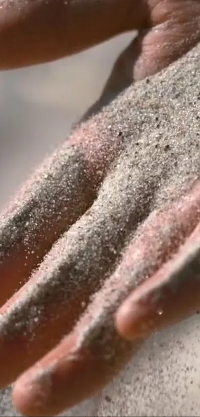 Close-up of a hand partially covered in soft sand, creating a calming effect.